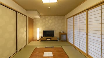 A traditional Japanese room with tatami flooring, a television, a cabinet, and sliding doors.