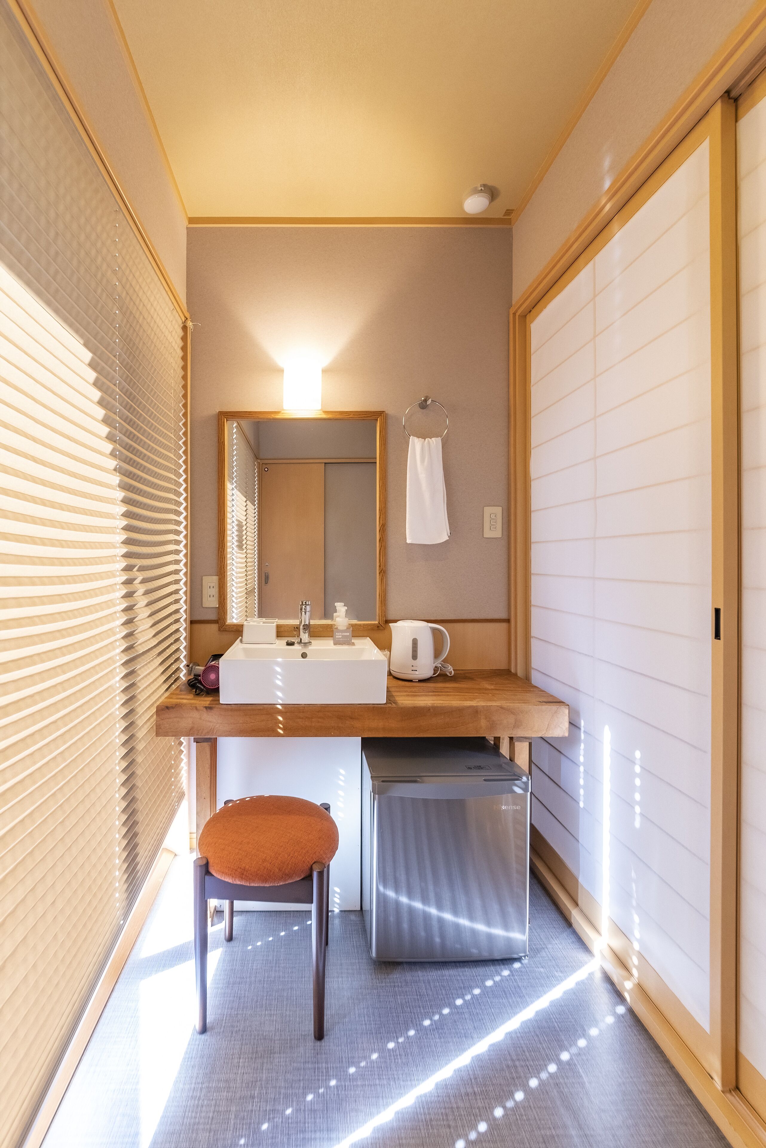A modern bathroom with a wooden vanity, a mirror, a sink, a towel rack, and a toilet.