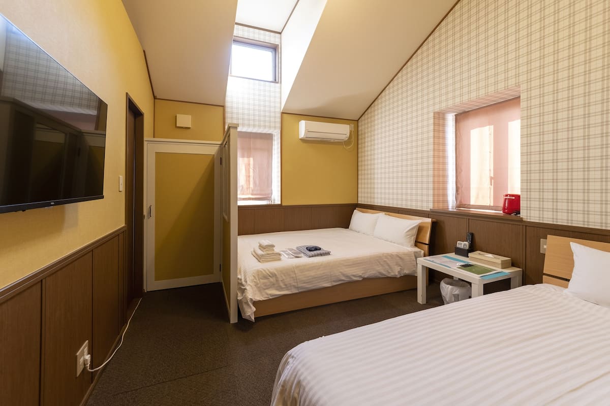 Quarto de hotel com cama, mesa de cabeceira e televisão.