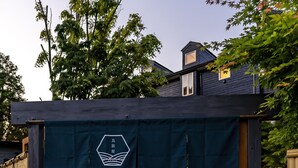 Een poort met een bordje, een stenen muur en een pad dat naar een gebouw leidt.