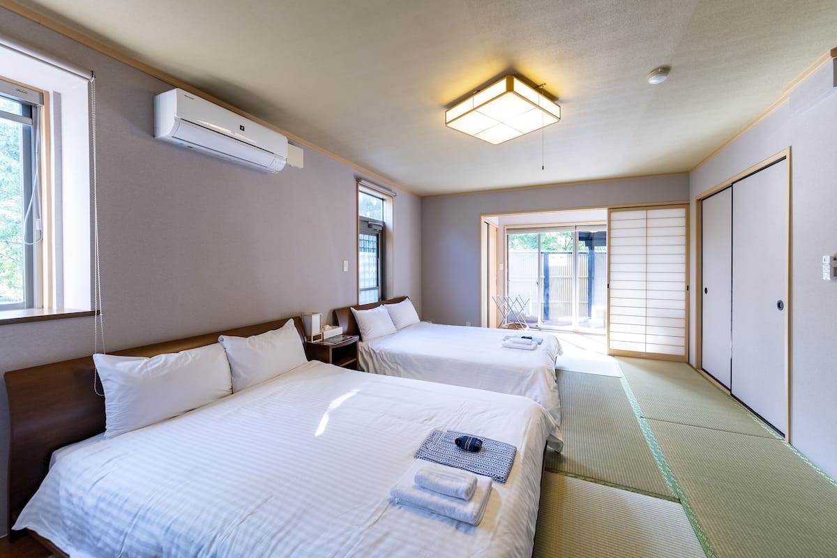 Quarto de hotel com duas camas, uma luminária no teto e vista para o exterior.