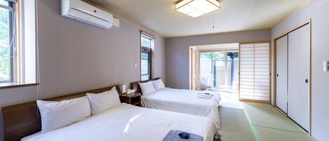Habitación de hotel con dos camas, una lámpara en el techo y vistas al exterior.