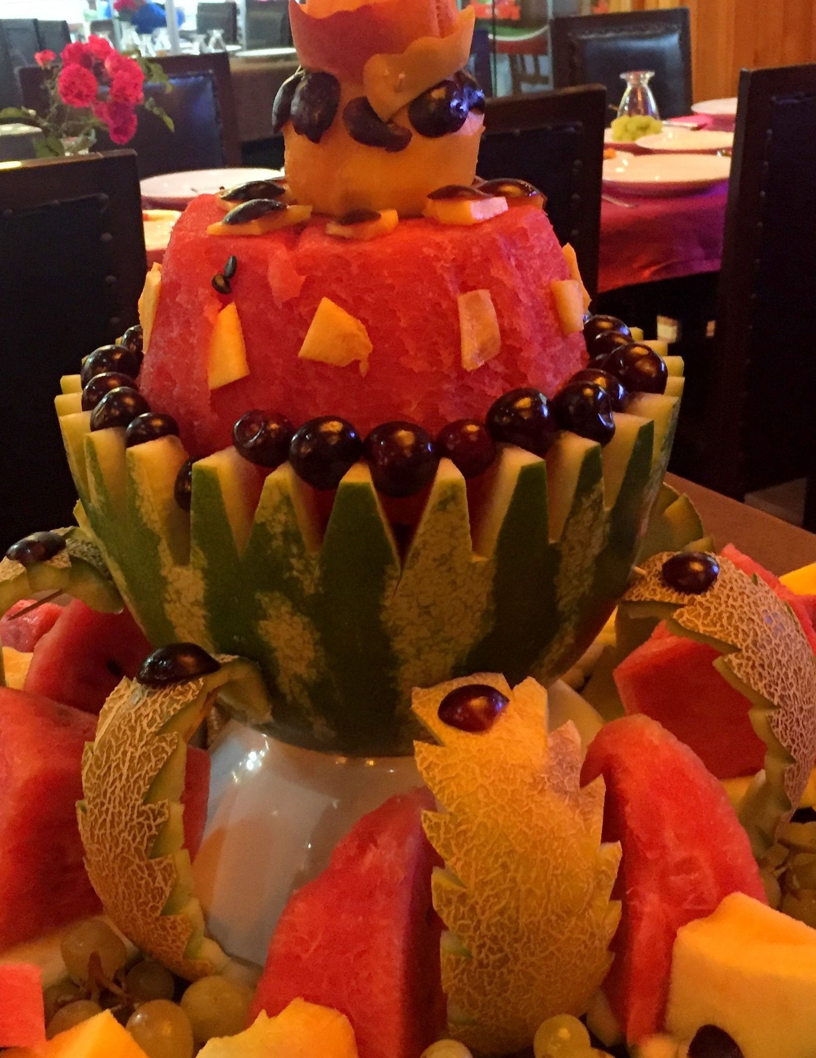Un centro de mesa con frutas y verduras dispuestas en varios niveles sobre una mesa.