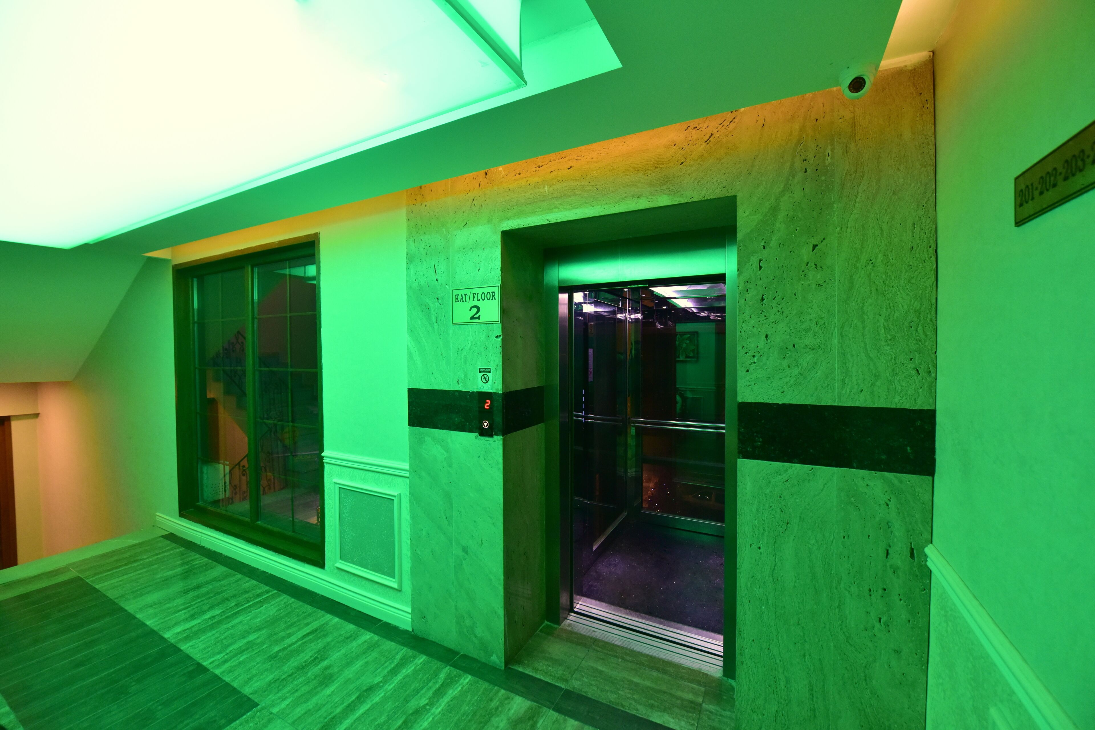 An elevator with a sign indicating 'Kati Floor 2' and a visible emergency phone.