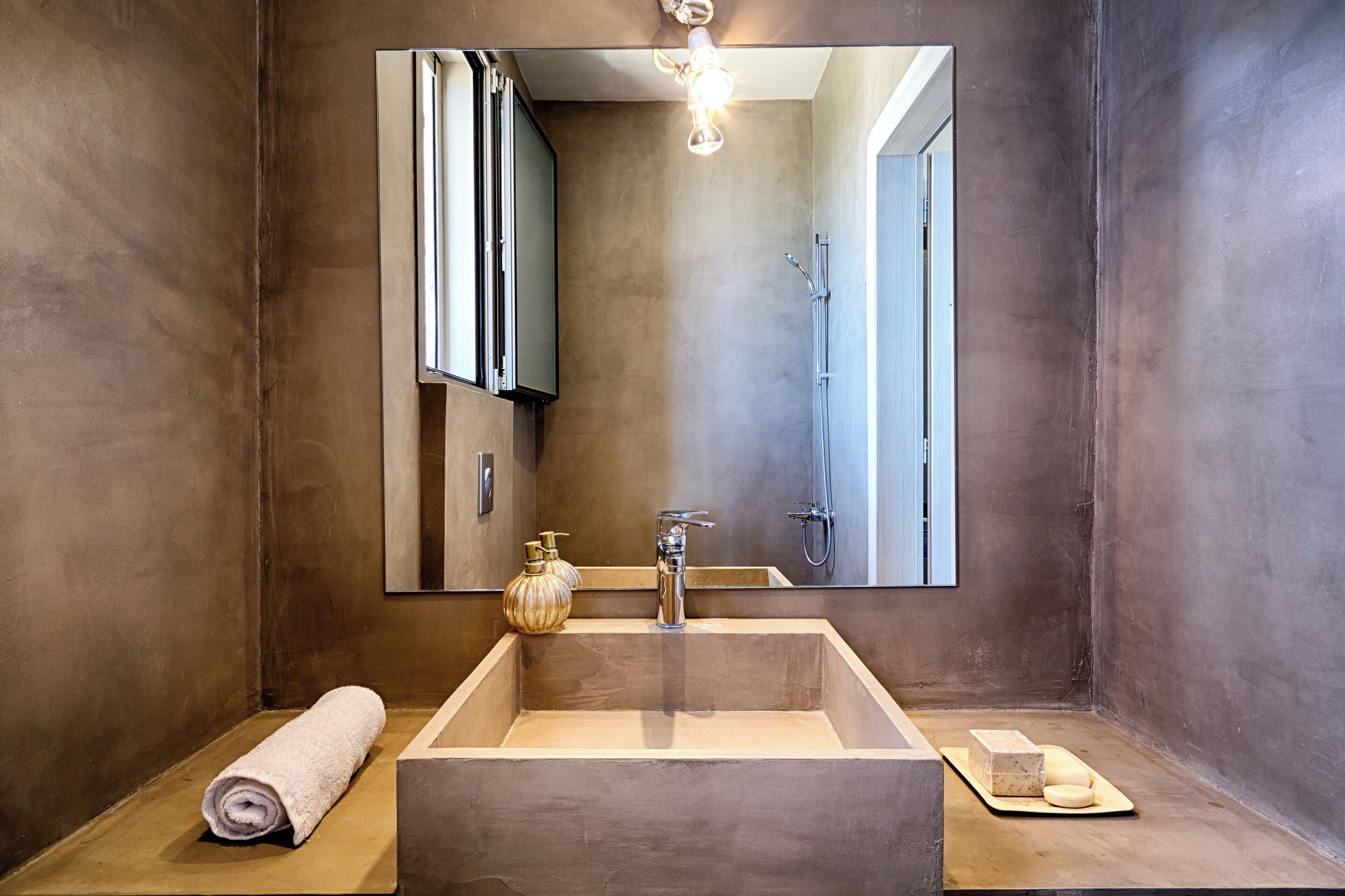 A modern bathroom with a large mirror, a rectangular sink, and a towel on the floor.