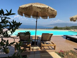Una piscina al aire libre, sombrillas, sillones reclinables de piscina