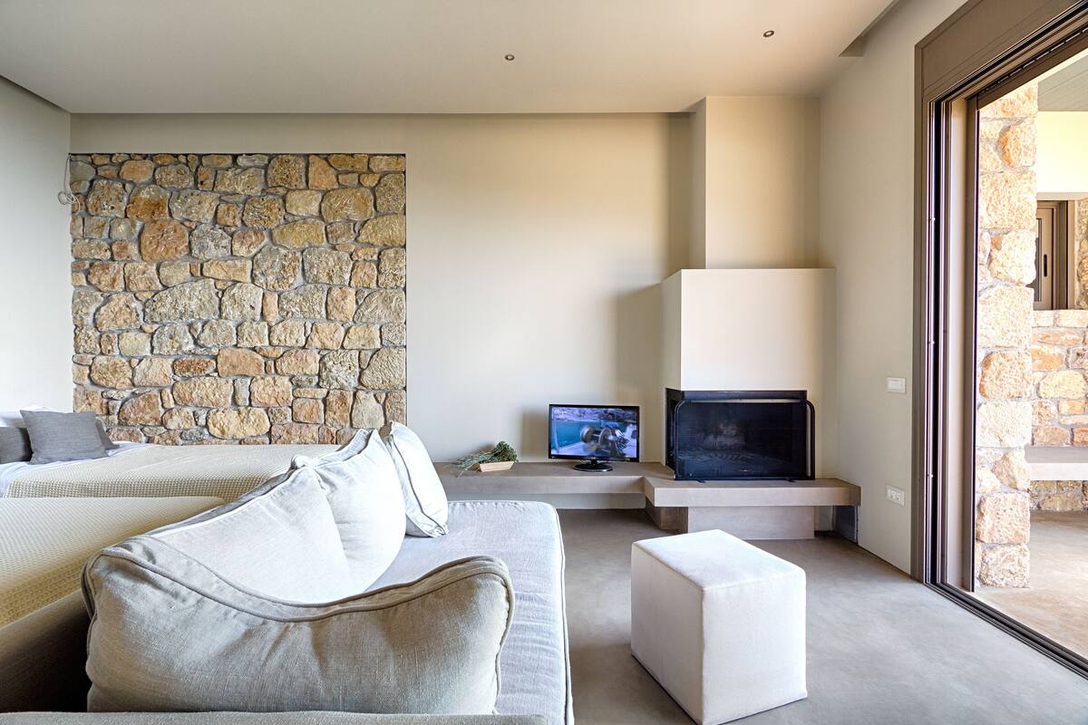 Une chambre moderne avec un mur en pierre, un téléviseur à écran plat, un canapé et une grande fenêtre.