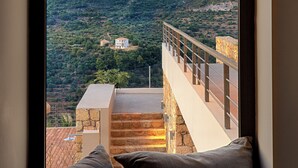 Habitación con vistas a un paisaje montañoso, un balcón con barandilla y una pared de piedra.