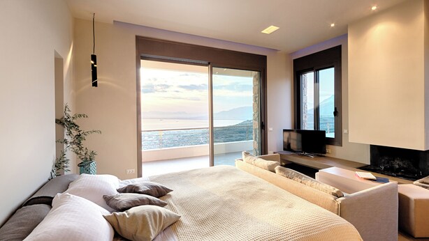Un dormitorio moderno con una cama grande, un televisor y vistas al mar.