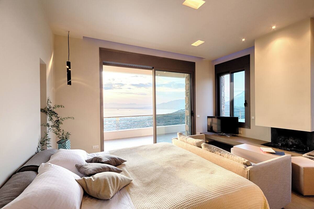 Une chambre moderne avec un grand lit, une télévision et une vue sur la mer.