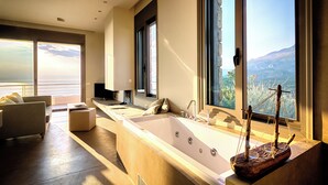 Un baño moderno con una bañera grande, una decoración náutica de madera y vistas a las montañas a través de amplios ventanales.