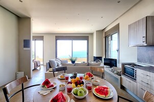 A modern kitchen with a dining area, large windows, and a view of the ocean.