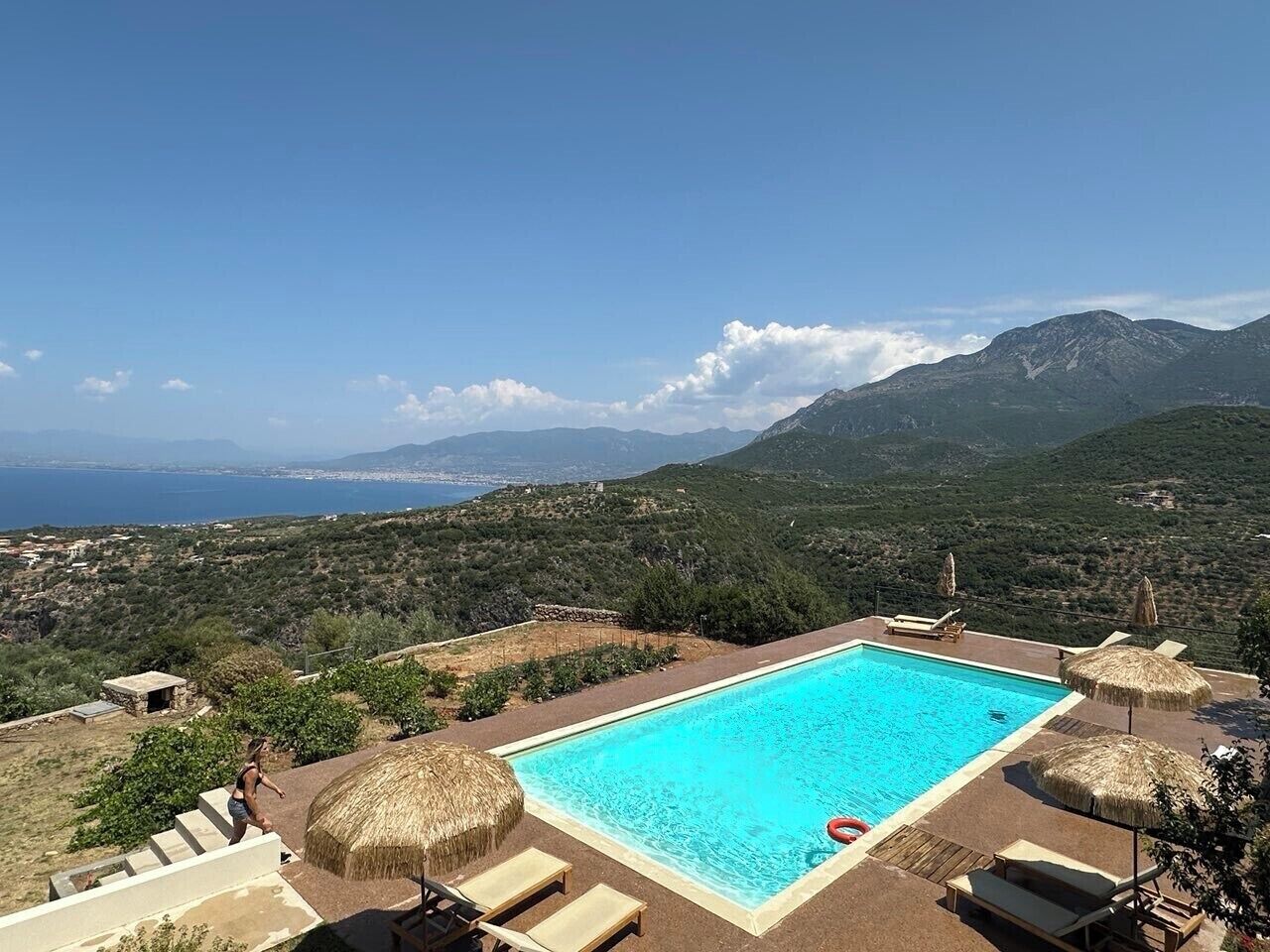 A pool with a clear view of the sea and mountains in the background.