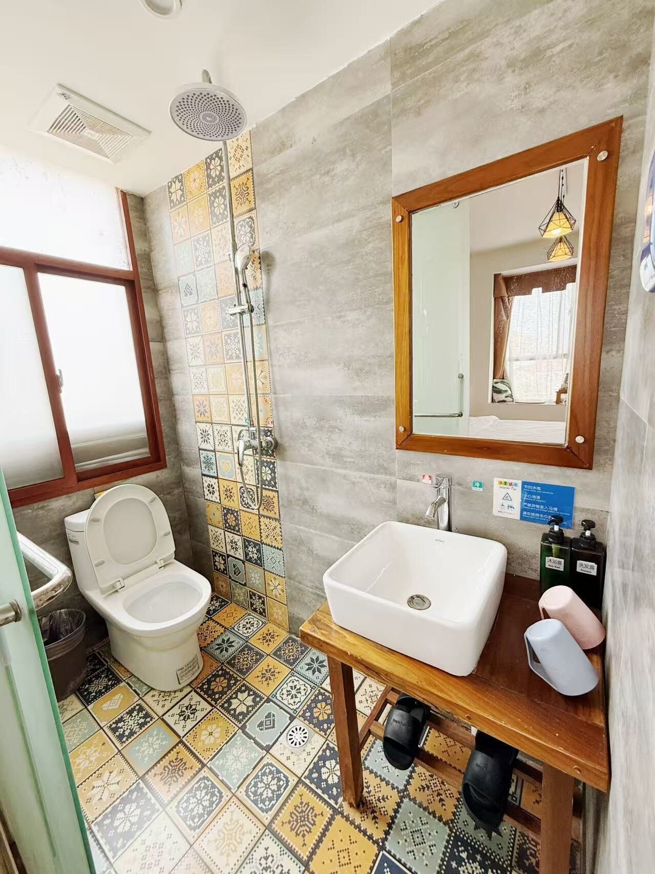 A bathroom with a toilet, shower, sink, and a mirror.