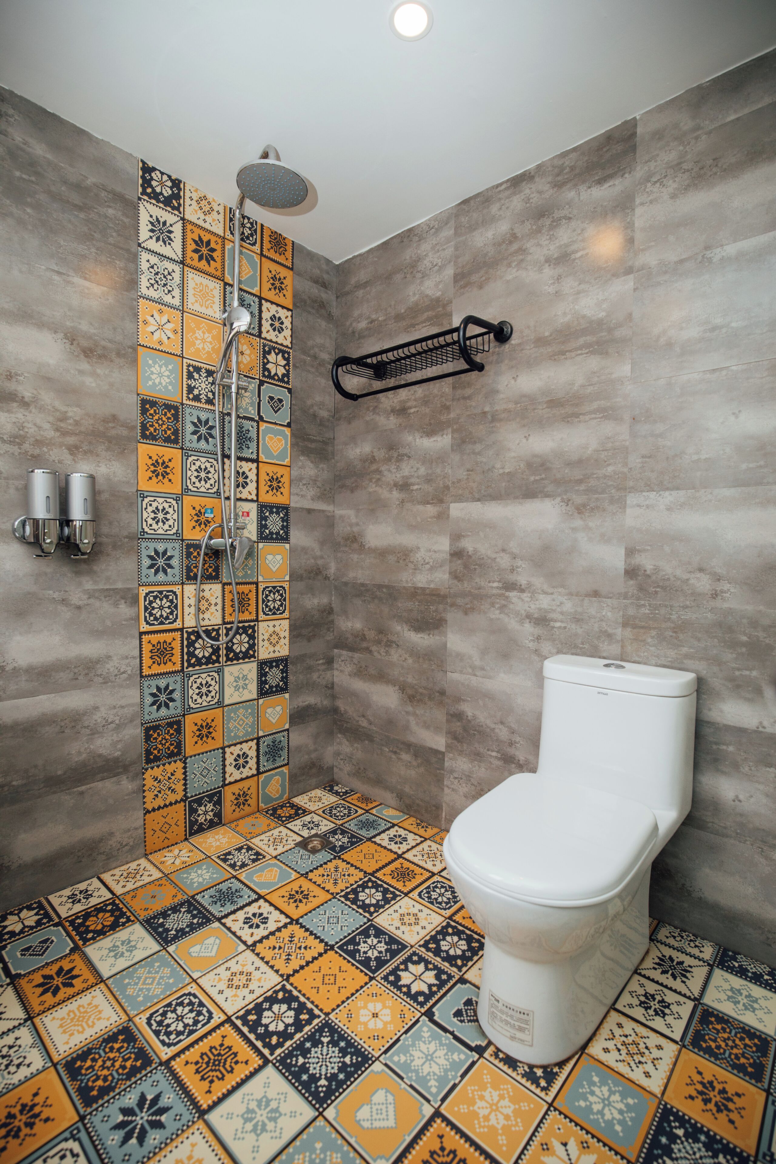 A bathroom with a shower, toilet, and tiled floor.