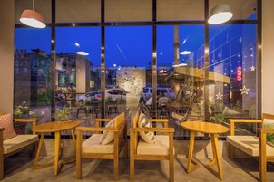Un interno moderno con ampie finestre, arredamento in legno e vista sulla città illuminata di notte.