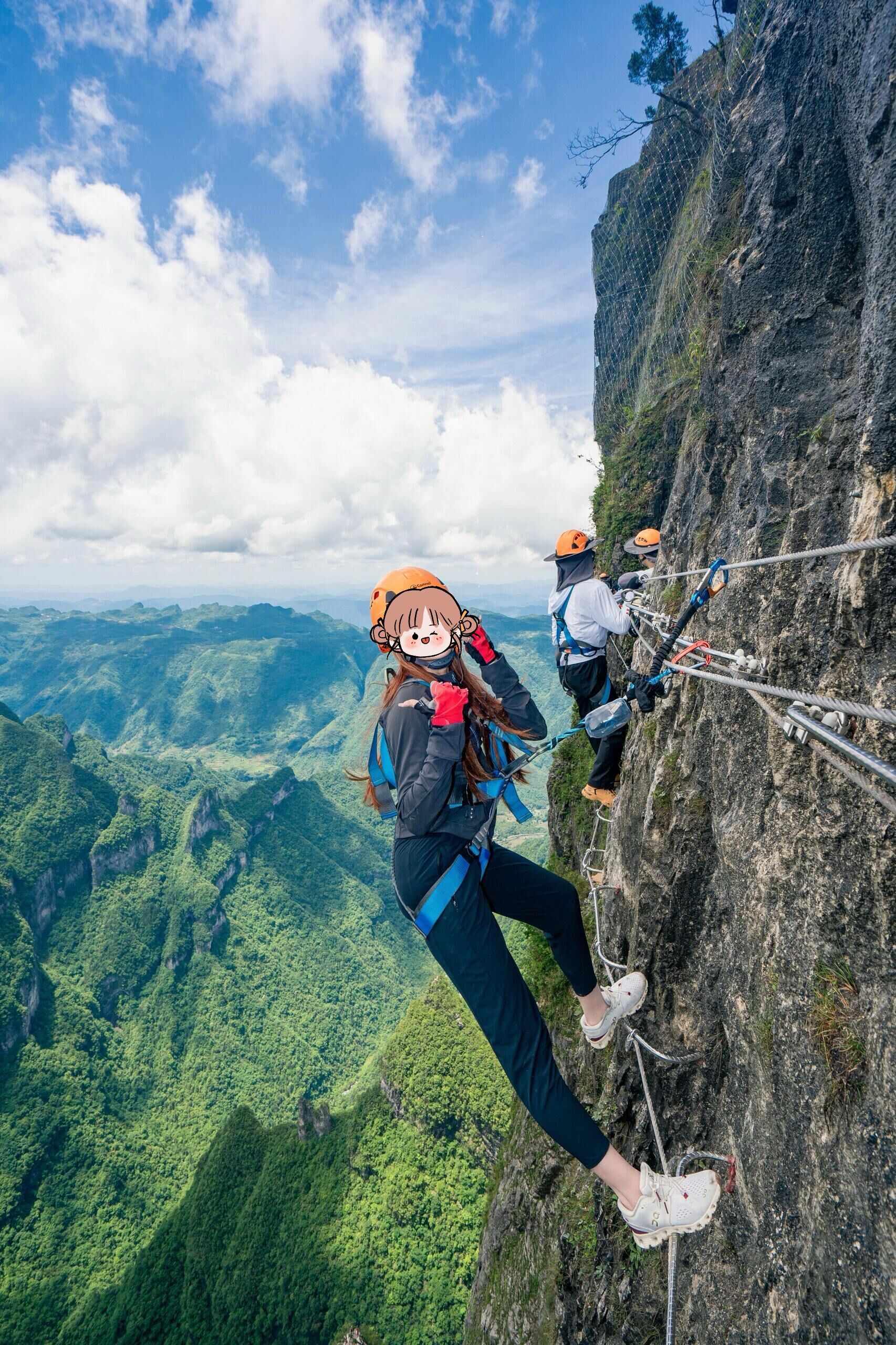 Una persona haciendo rappel por un risco, con una vista panorámica de un valle boscoso abajo.