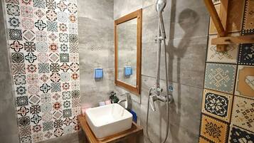 A bathroom with a sink, mirror, shower, and patterned tiles.