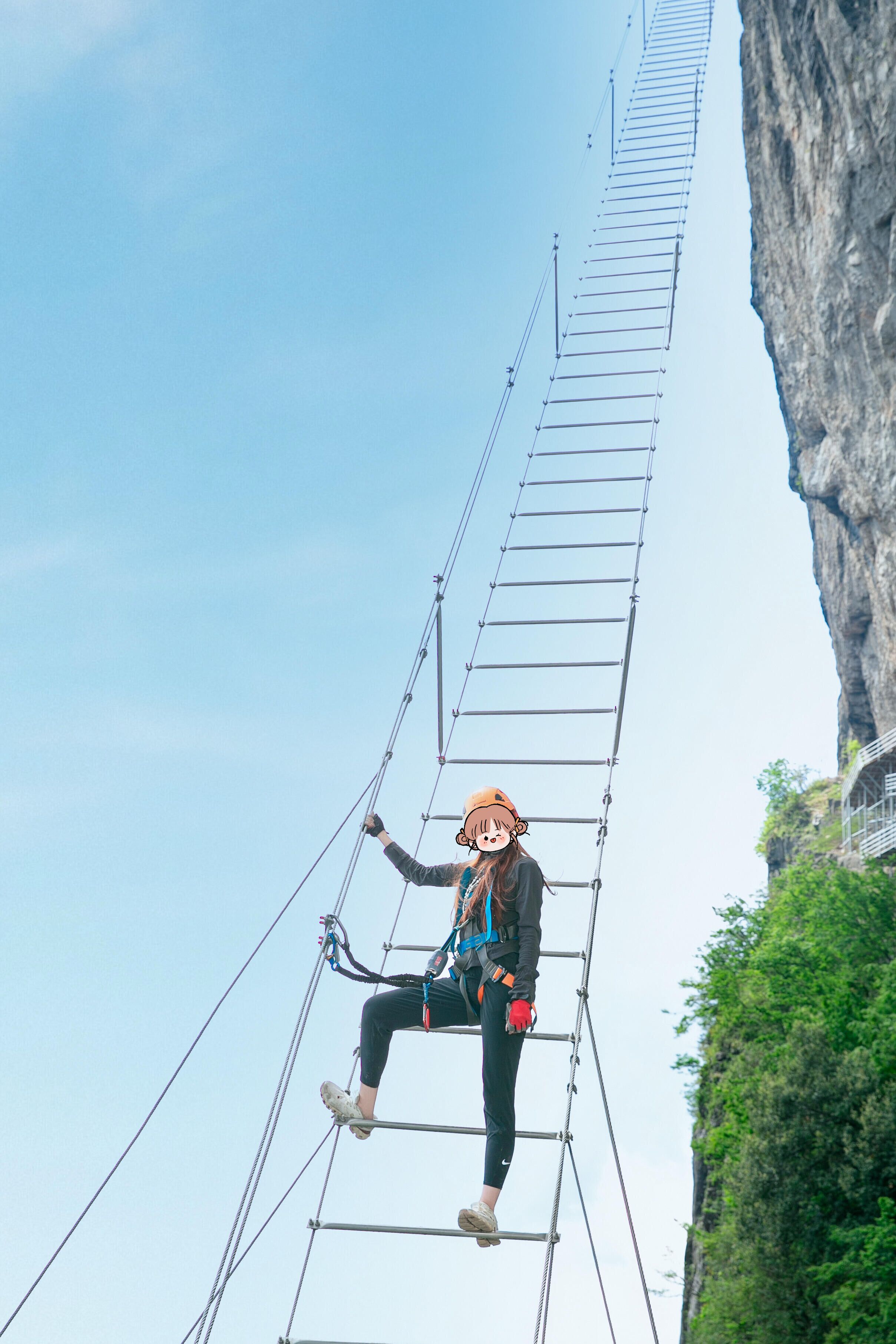A person on a metal ladder against a cliff.