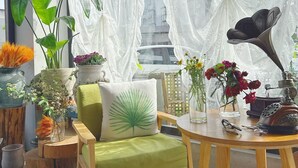 A room with a green sofa, a wooden table, and various potted plants. - Zhang Jiajie Zhijue Art Hotel (Zhangjiajie)