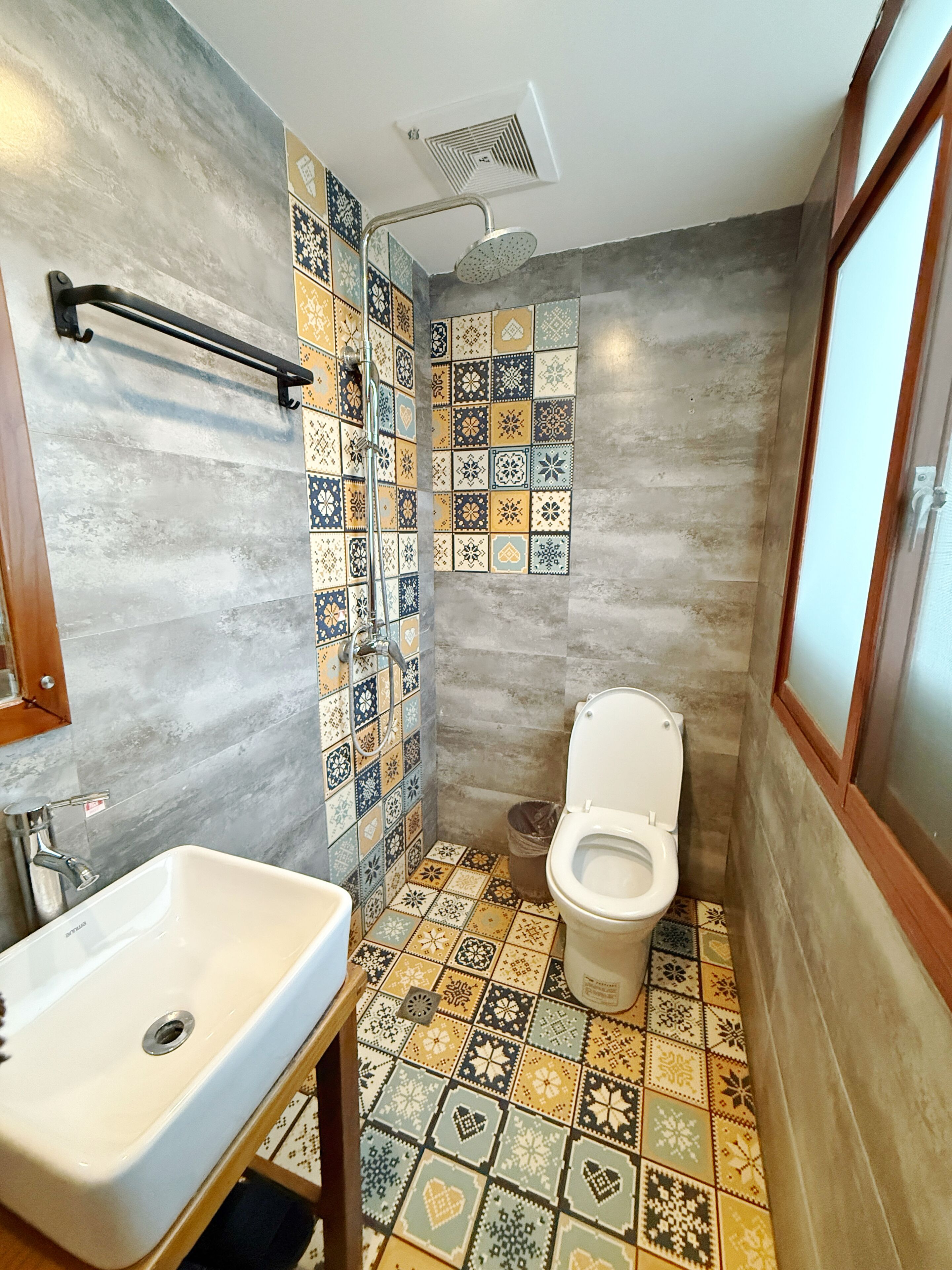 Ein Badezimmer mit gefliestem Boden, einem Waschbecken, einer Toilette und einer Dusche.