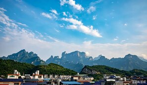 A mountainous landscape with a town in the foreground and a clear sky above. - Zhang Jiajie Zhijue Art Hotel (Zhangjiajie)