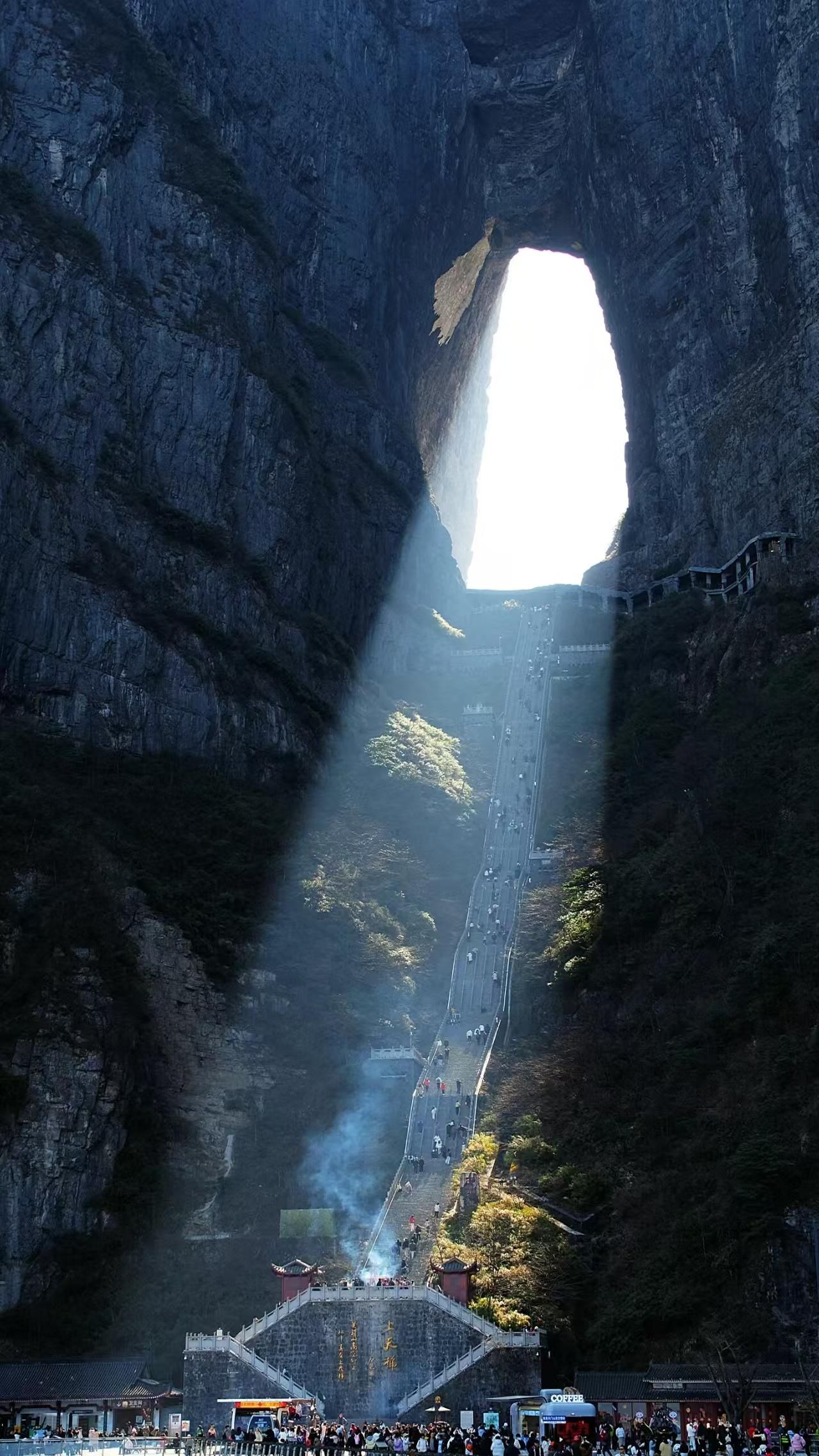 Una gran formación rocosa con un arco natural y una plataforma de observación en la base.