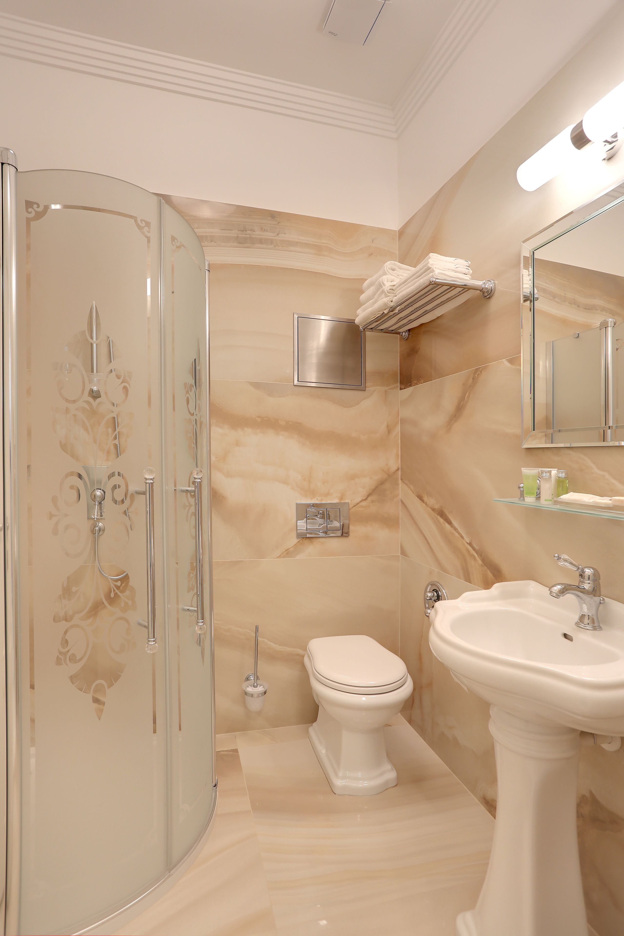 A bathroom with a glass shower enclosure, a toilet, and a pedestal sink.
