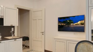A dining area with a table set for two, a chandelier, and a television on the wall. - Ferdinandhof Apart-Hotel (Karlovy Vary)