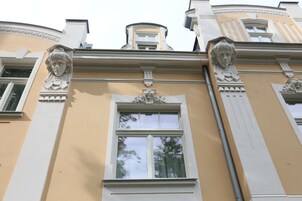 Fachada de edificio con detalles arquitectónicos clásicos, incluyendo esculturas ornamentales y un amplio ventanal.