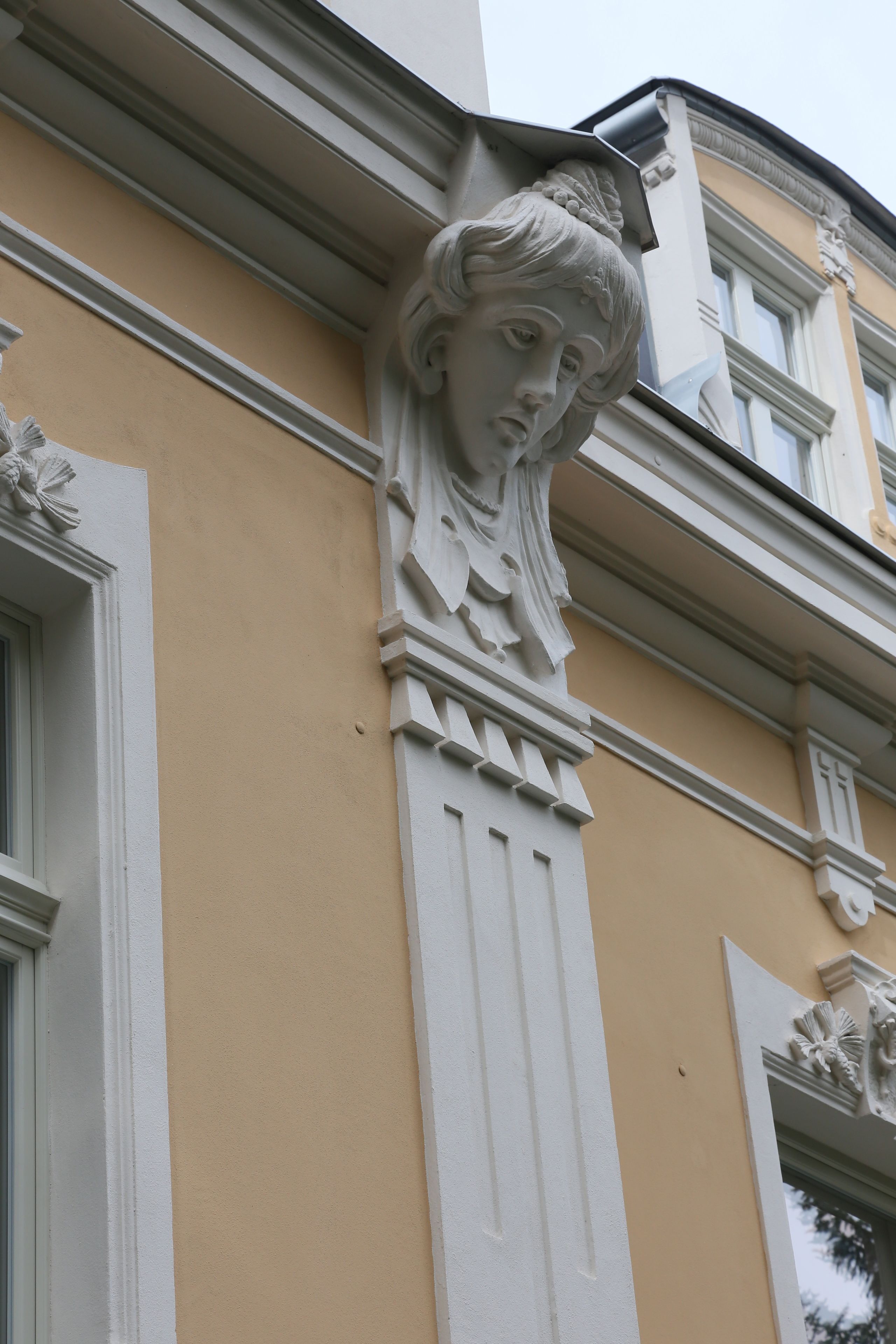 Esquina de un edificio con una decoración de piedra tallada y una ventana.