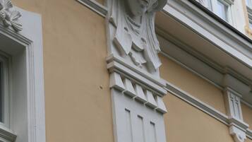 A building corner with a decorative stone carving and a window.