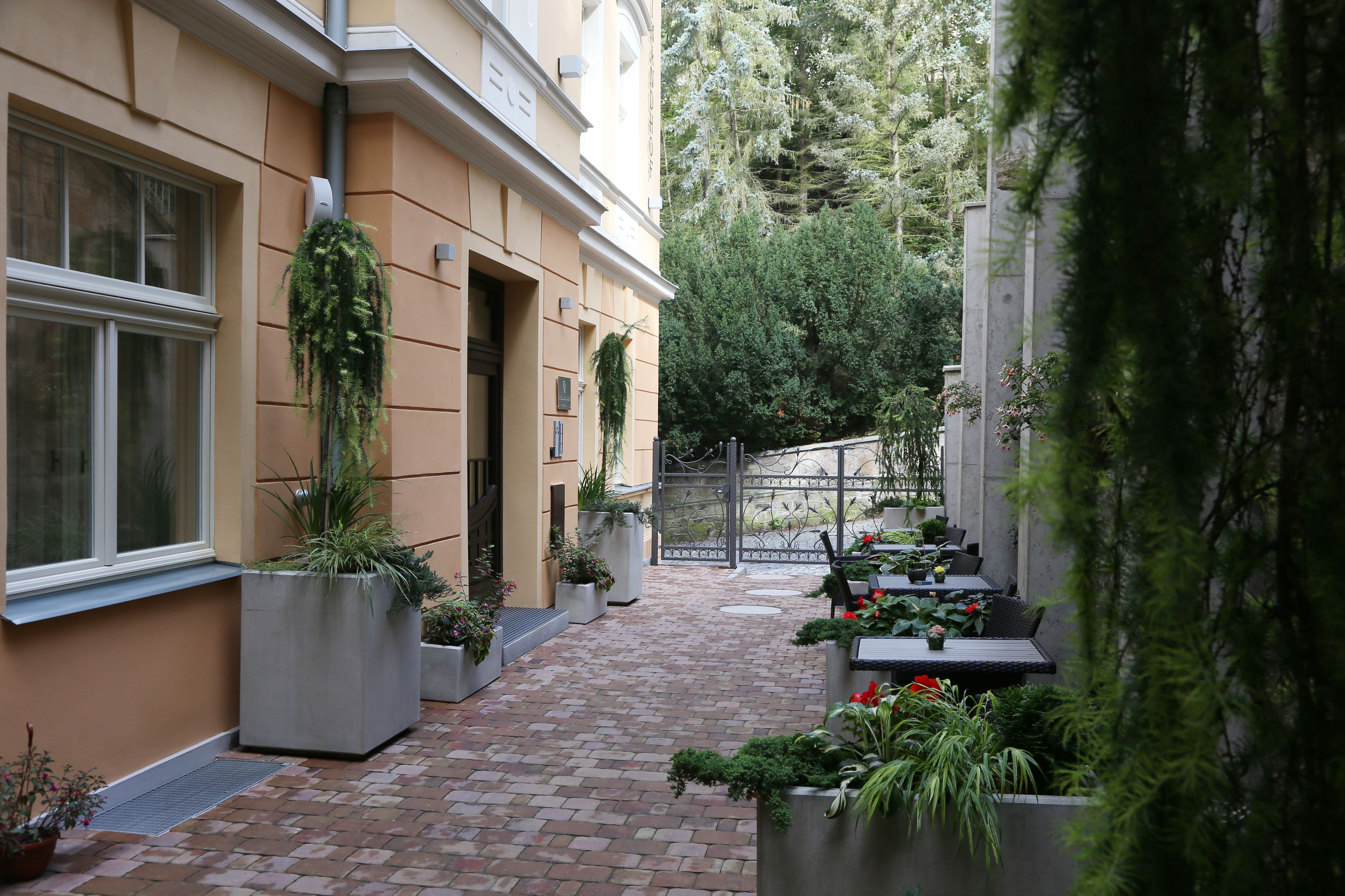 A courtyard with a brick pathway, potted plants, and outdoor seating.