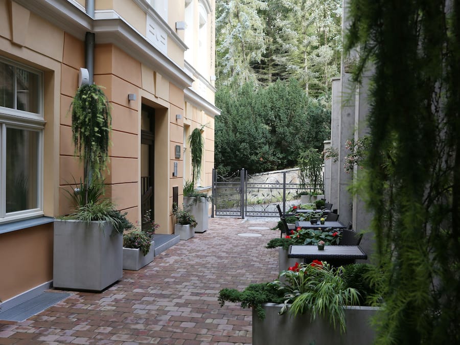 A courtyard with a brick pathway, potted plants, and outdoor seating.