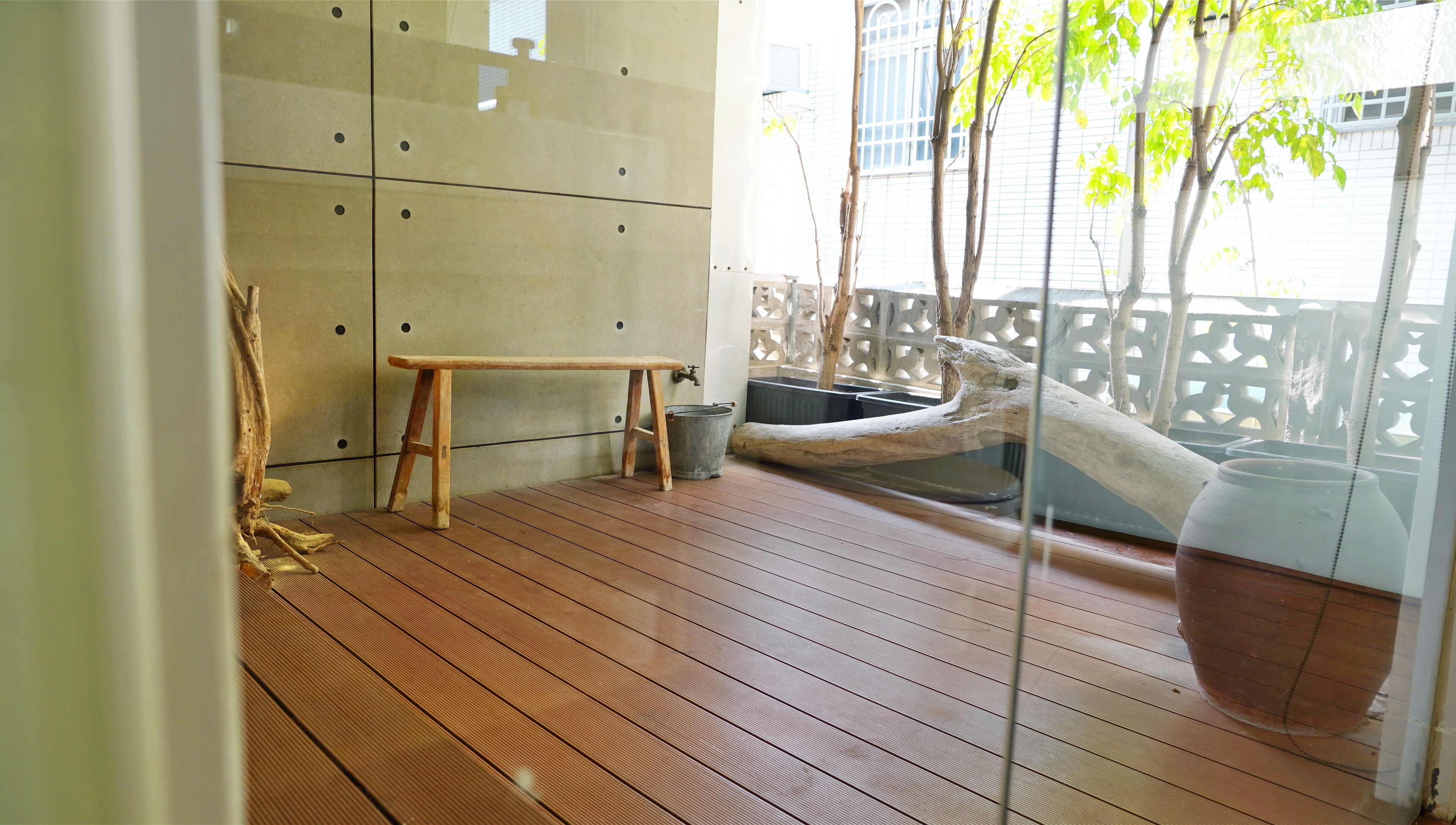 A wooden deck with a bench, a bucket, and a large pot.