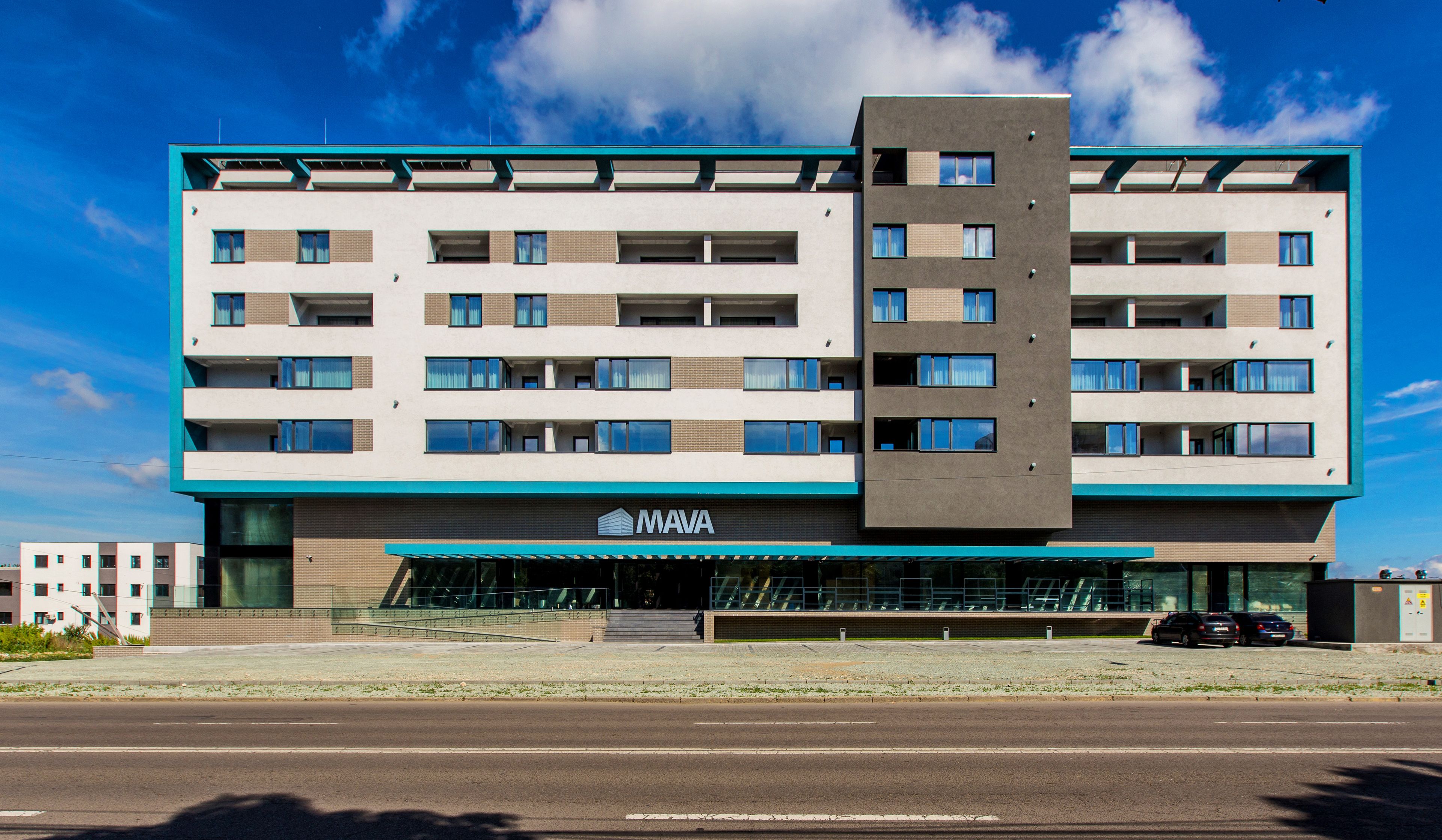 Un hotel de varios pisos con un diseño moderno, que cuenta con una entrada destacada con puertas de vidrio y un cartel que dice "MAVA".