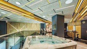A modern spa area with a hot tub, exercise equipment, and a glass railing overlooking a lower level. - Mava Apartamente (Constanta)