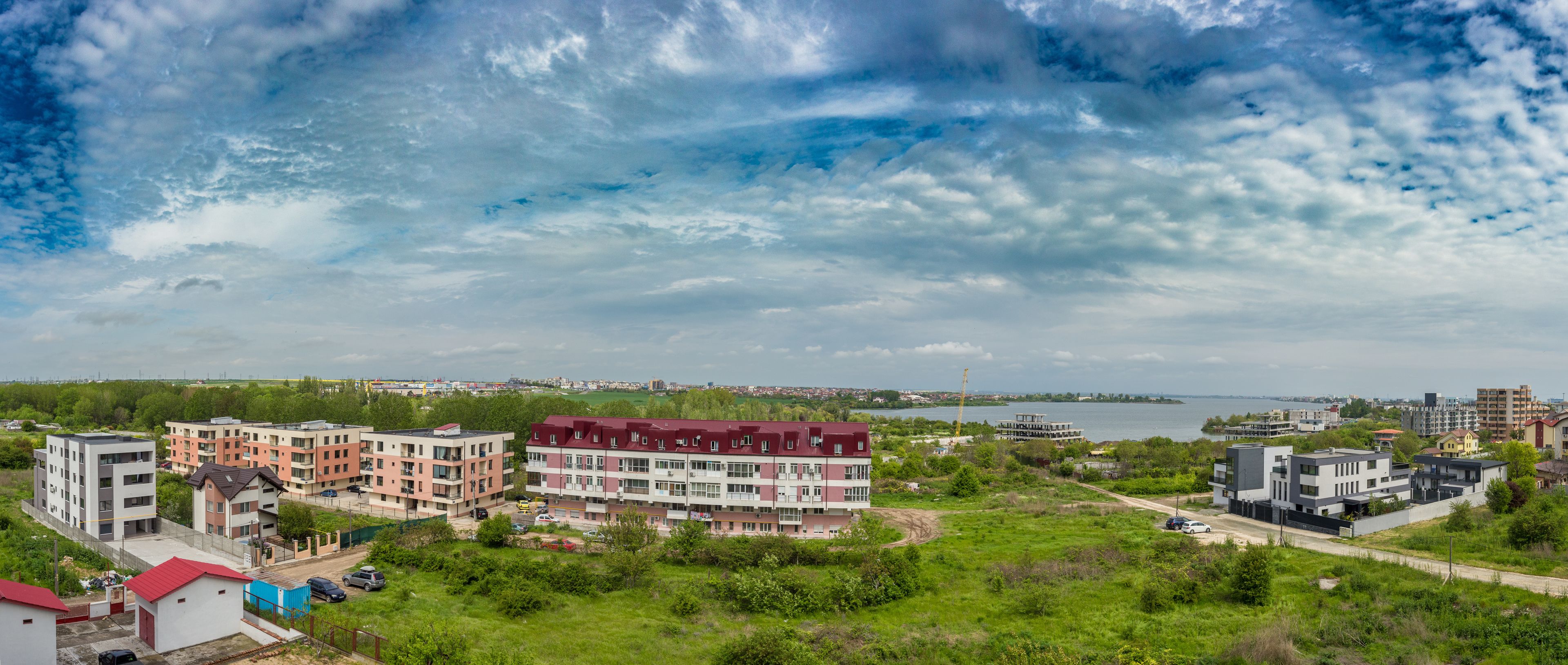A residential area with multi-story buildings, a body of water, and a distant city skyline.