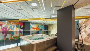 A modern bathroom with a large bathtub, a glass shower enclosure, and a colorful mural on the wall.