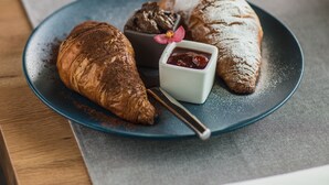 A plate with a croissant, a chocolate dessert, and a small bowl of jam on a blue plate.