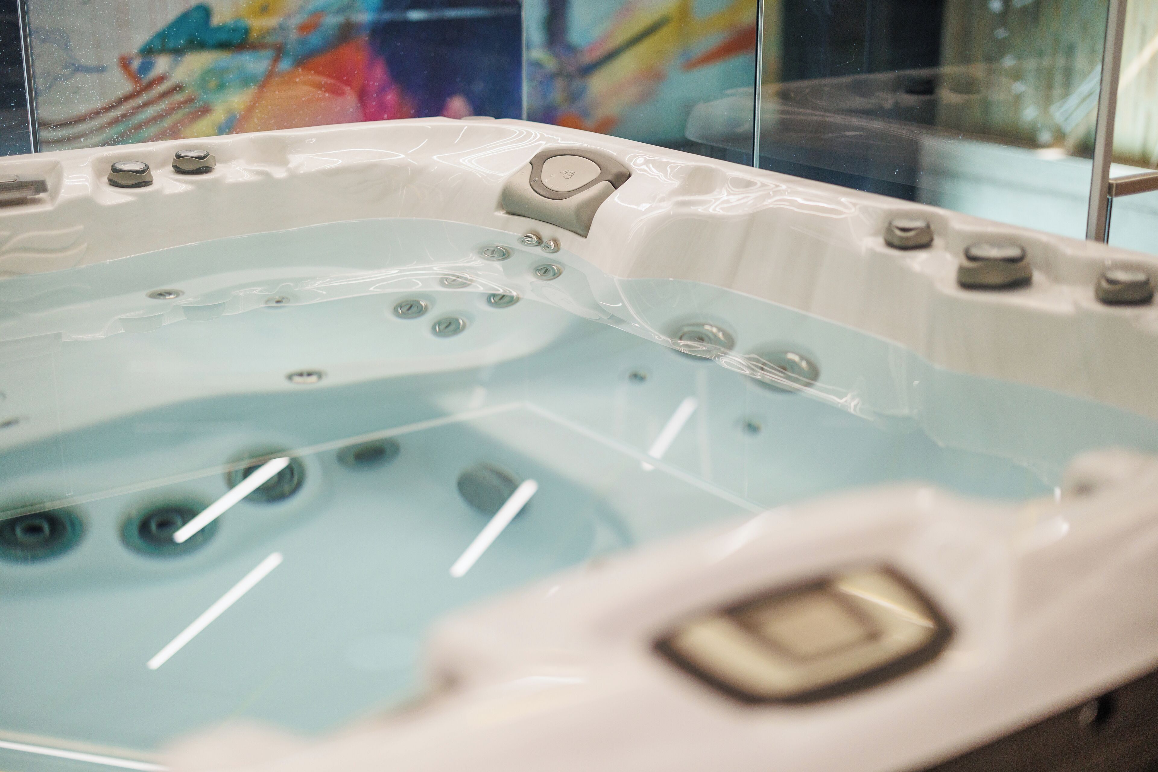 Een jacuzzi met meerdere jets, een bedieningspaneel en een glazen ombouw.