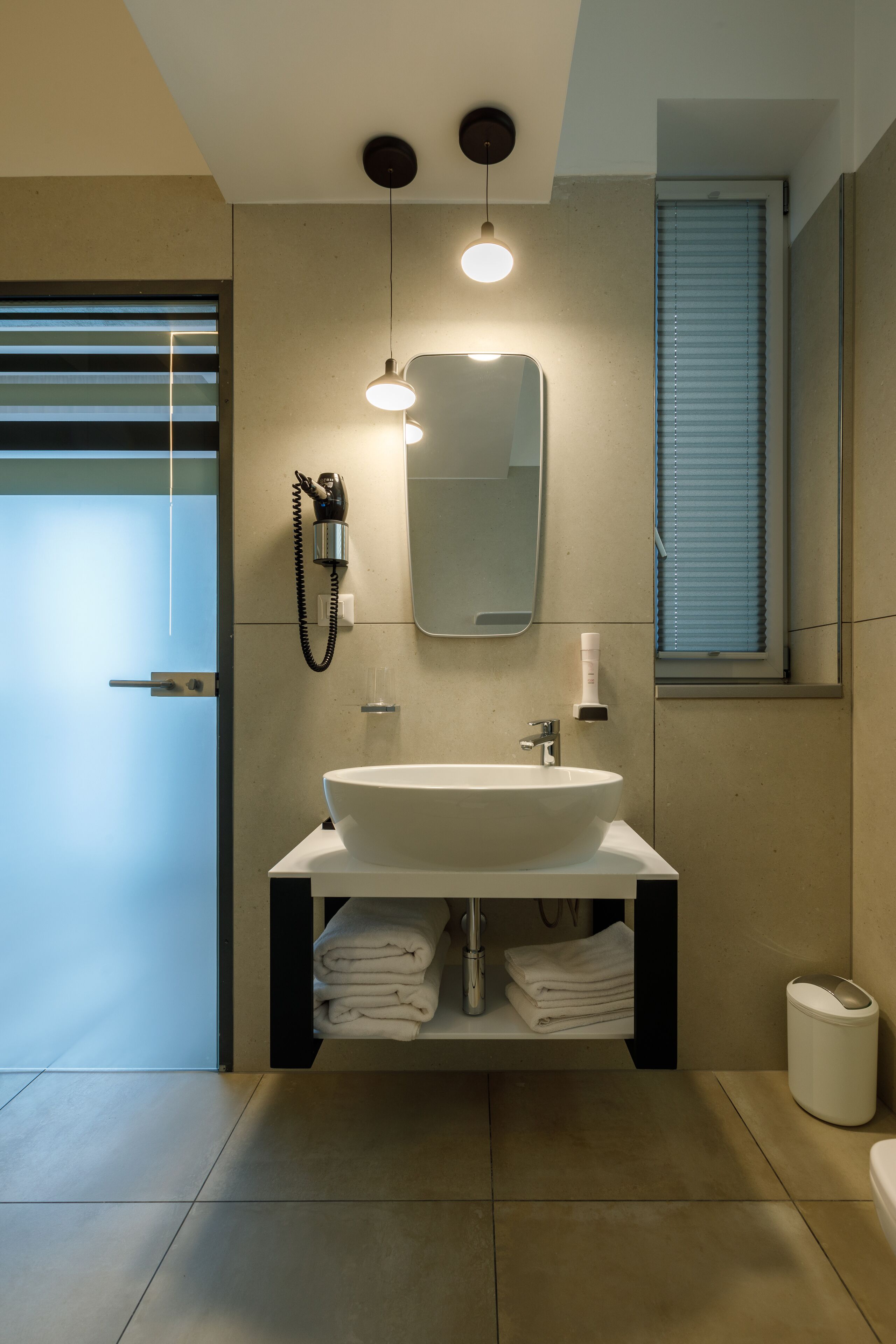 A modern bathroom with a large sink, a mirror, and a towel rack.