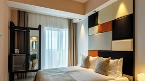 A hotel room with a large bed, a mirror, a bedside table, and a view of a bathroom.