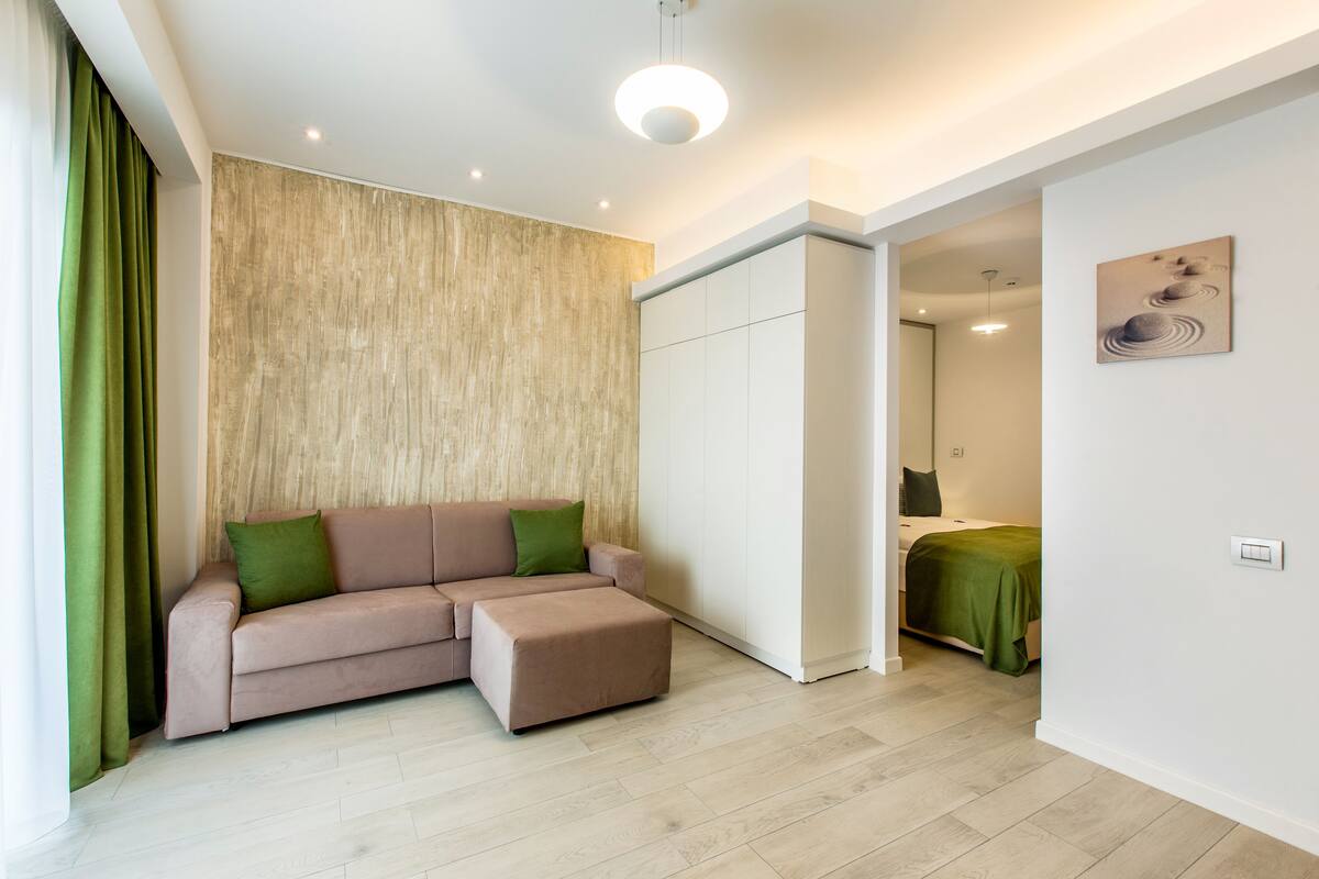 A modern living room with a sofa, ottoman, and a wooden accent wall.