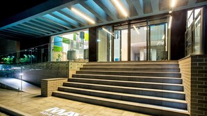 A modern building entrance with a staircase leading to a glass door, a sign reading "MAVA apartament", and a well-lit outdoor area. - Mava Apartamente (Constanta)
