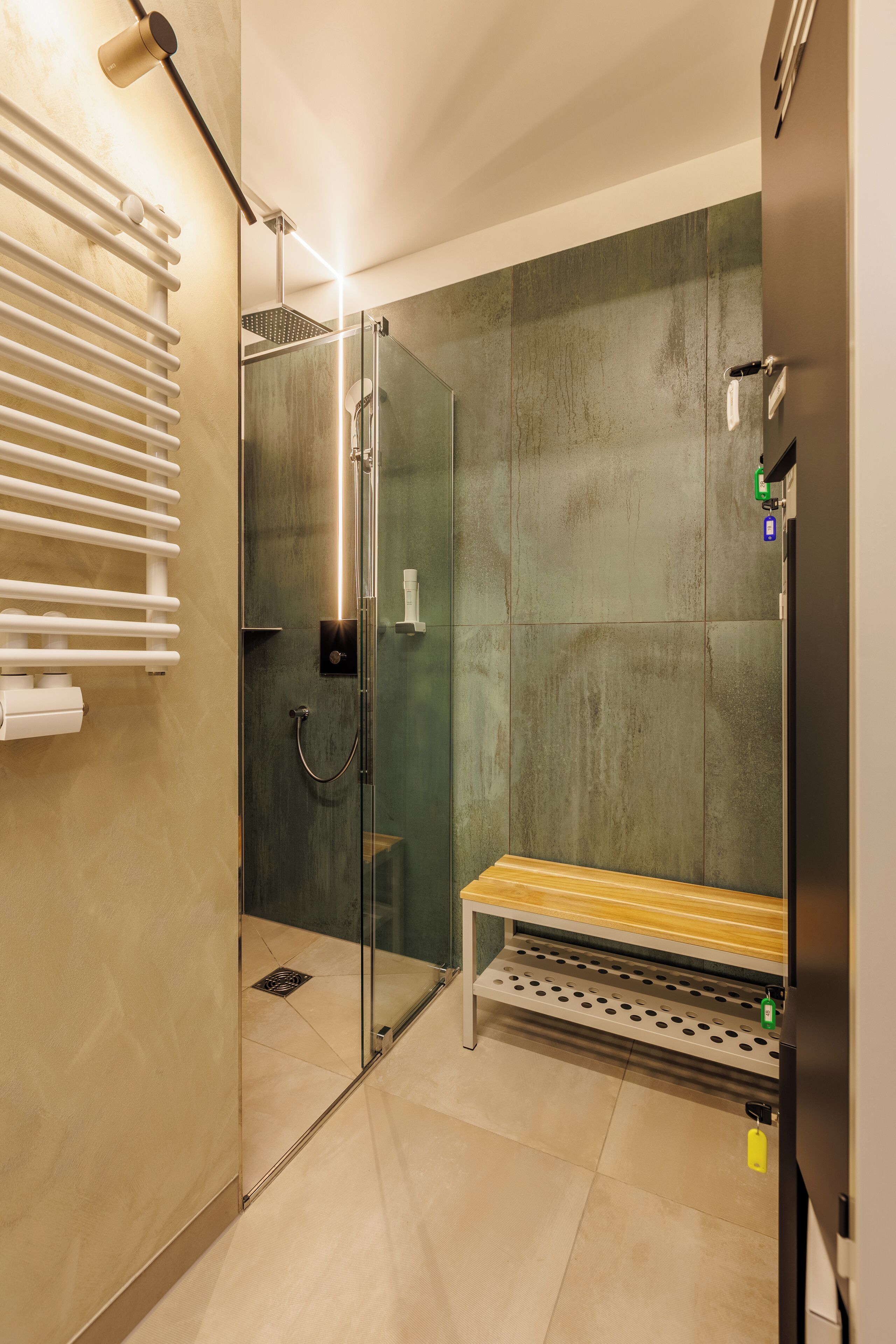 A modern shower area with a glass enclosure, a bench, and a towel rack.