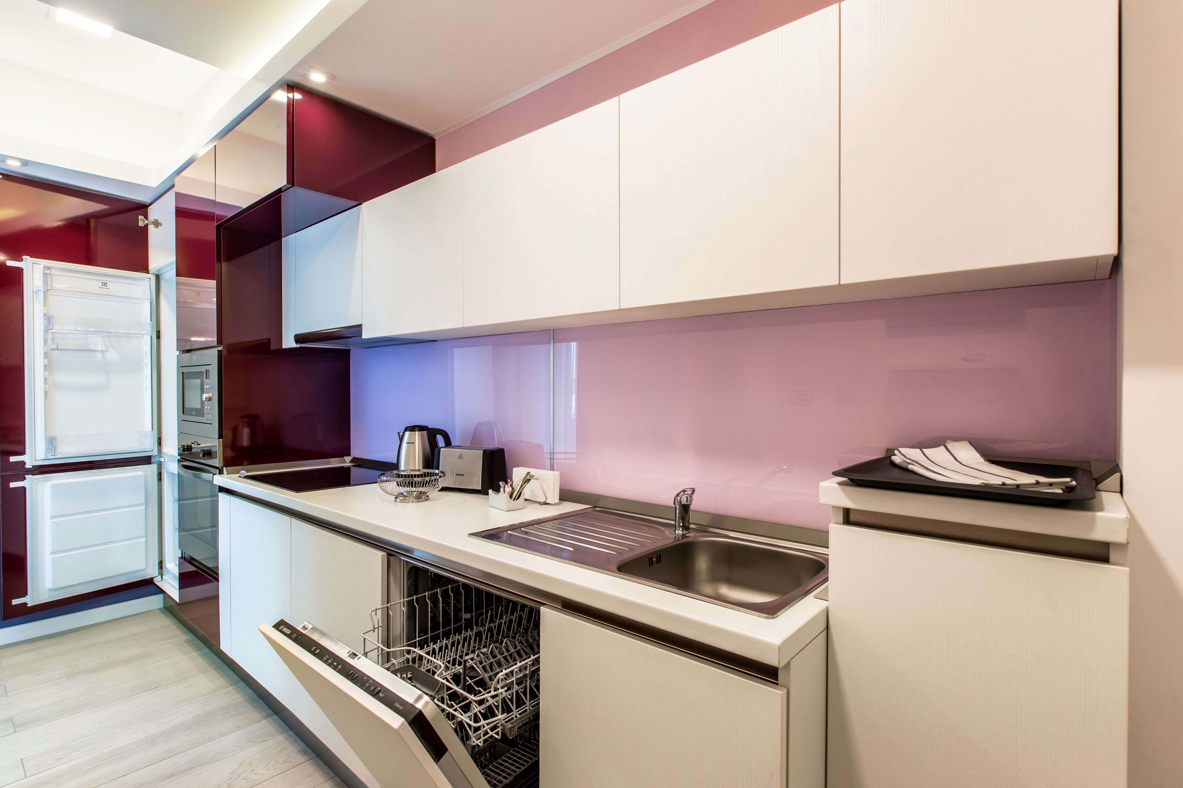 A modern kitchen with white cabinets, a stainless steel sink, and a dishwasher.