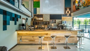 A modern bar area with a wooden counter, bar stools, and a variety of bottles and glasses. - Mava Apartamente (Constanta)