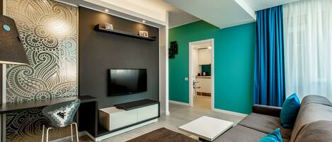 A modern living room with a flat-screen TV, a sofa, a coffee table, and a patterned wall.