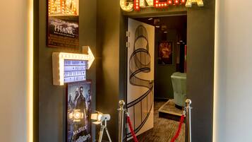 A cinema entrance with a neon sign, directional arrows, and movie posters.
